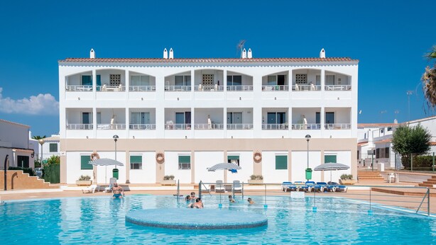 A multi-story hotel with a swimming pool, balconies, and outdoor seating.