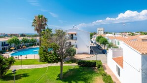 A residential area with a swimming pool, white buildings, and a clear blue sky.