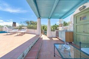 Un espace extérieur abrité comprenant une piscine, des chaises longues, une table en verre et une porte verte.