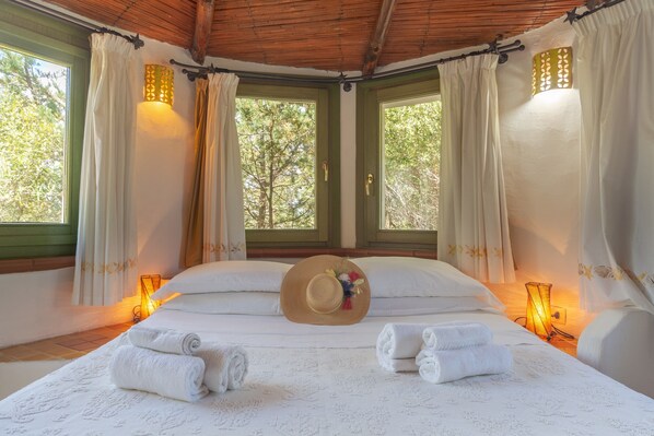 Une chambre avec un lit, des rideaux, un chapeau et des serviettes.