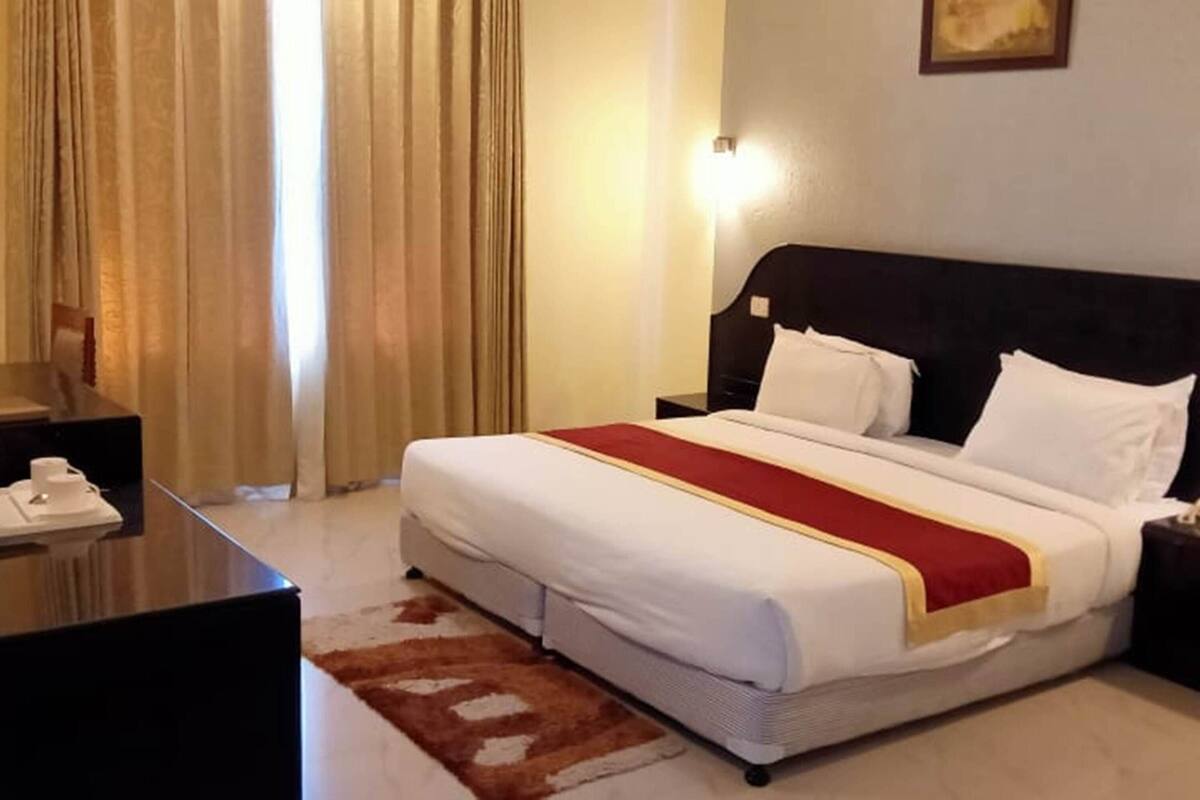 A hotel room with a large bed, two bedside tables, a desk, and a chair.