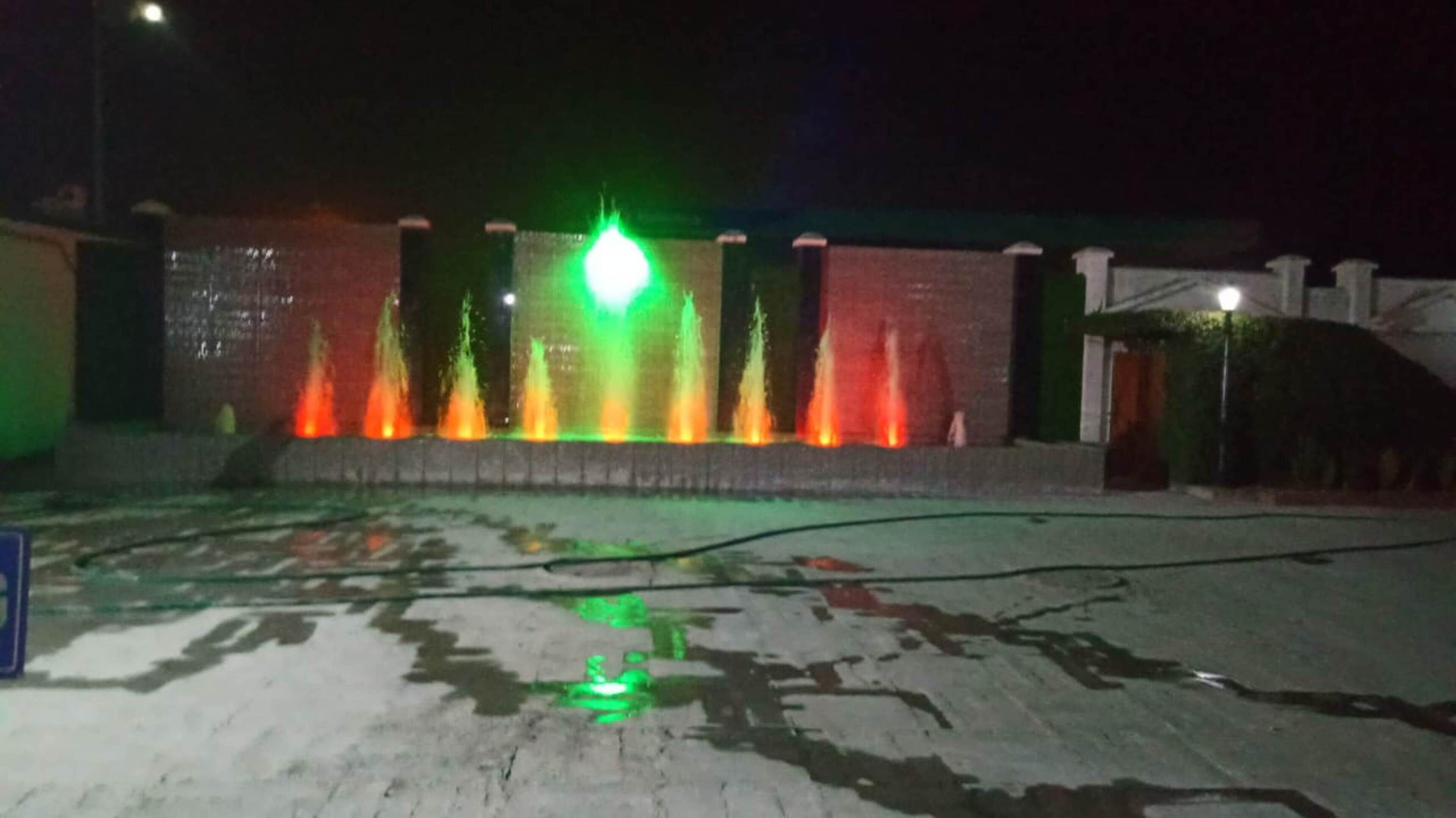 A nighttime view of a fountain with colorful lights.