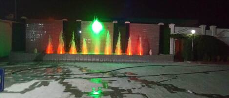 A nighttime view of a fountain with colorful lights.