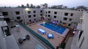 A rooftop pool area with multiple seating arrangements and a central pool.