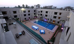 Un área de piscina en la azotea con varios espacios de descanso y una piscina central.