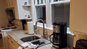 Ett kök med diskho, spis och kaffebryggare.