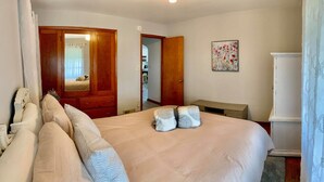 Une chambre à coucher avec un grand lit, une armoire en bois, une petite table et un tableau accroché au mur.