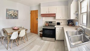 Une cuisine compacte avec un coin repas, comprenant une cuisinière, un four, un évier et un tableau accroché au mur.