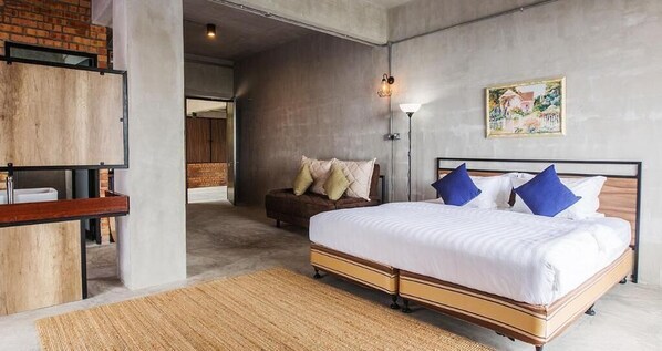 A bedroom with a large bed, a wooden bench, a wall-mounted light, and a painting. - Sembayu Villa (Seremban)