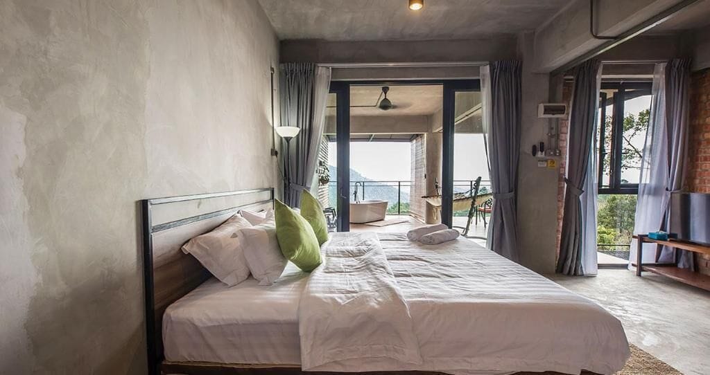 A bedroom with a large bed, a view of the outdoors, and a balcony.