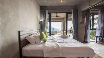A bedroom with a large bed, a view of the outdoors, and a balcony.