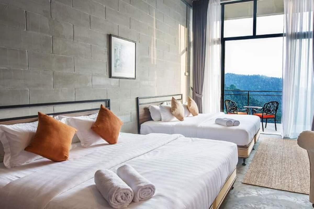 A hotel room with two beds, a balcony with a view, and a chair.