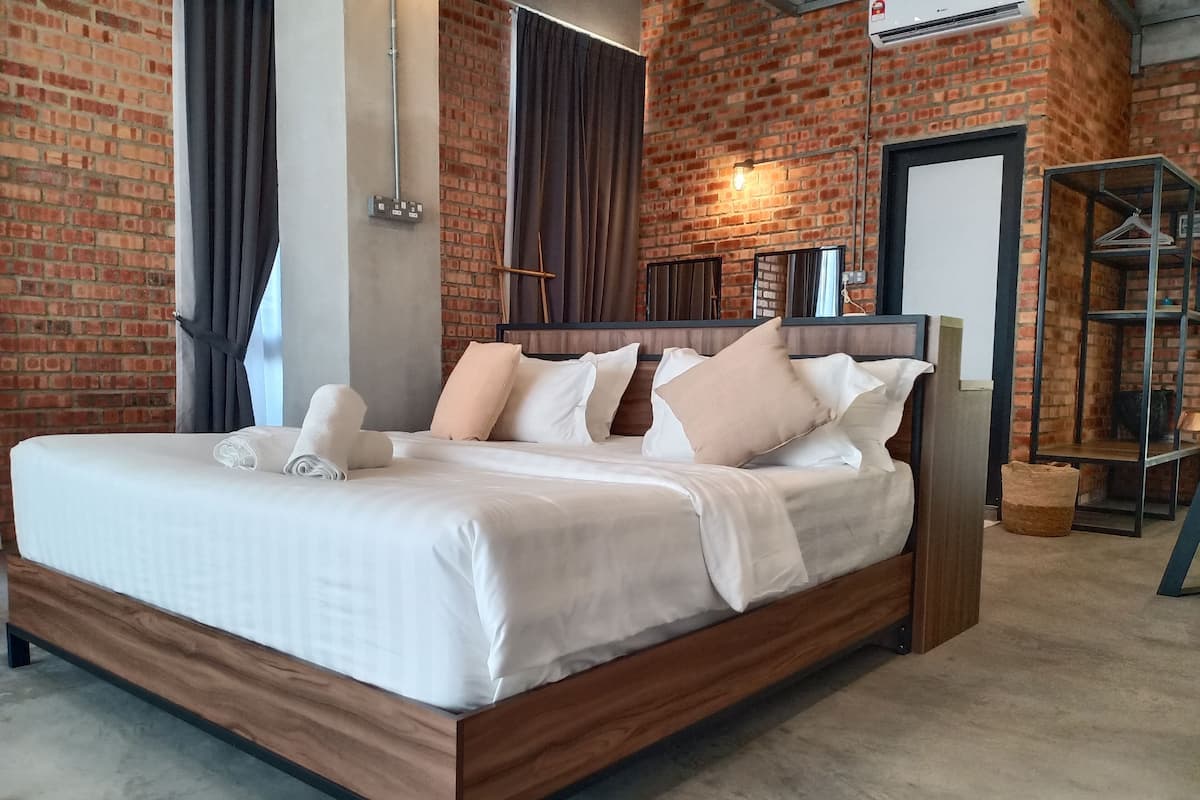 A modern hotel room with a brick wall, a wooden bed frame, and a metal headboard.