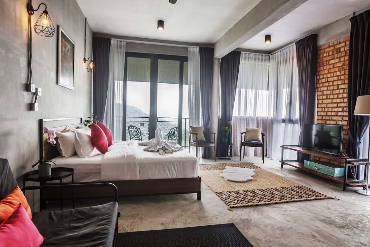 A hotel room with a bed, a TV, a balcony, and a view of the outdoors.