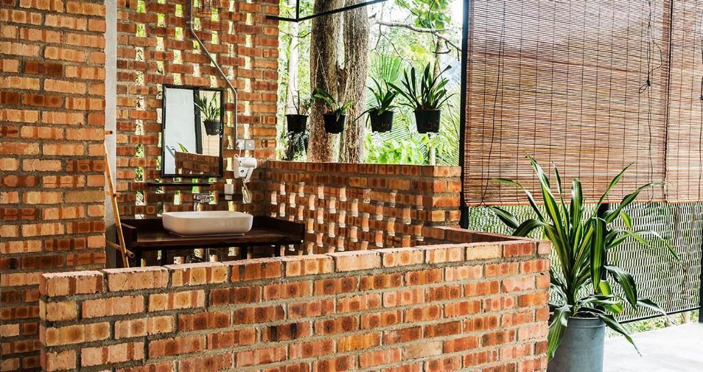 A bathroom with a brick wall, a sink, and hanging plants.