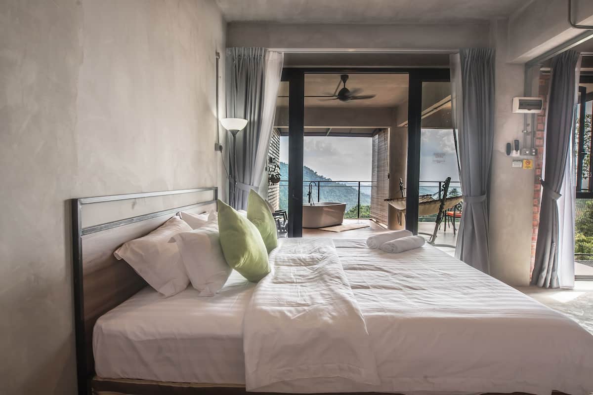 A hotel room with a bed, a view of the outdoors, and a balcony.