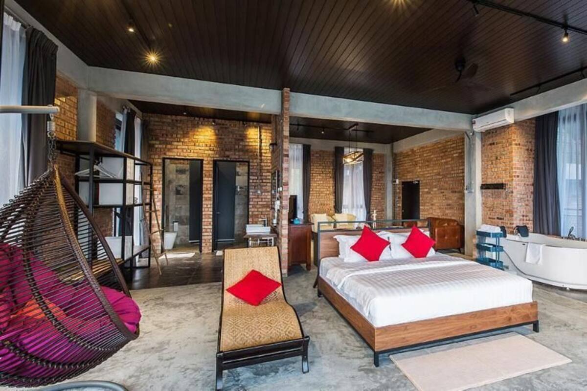 A spacious bedroom with a large bed, a sitting area, and a view of the outside.