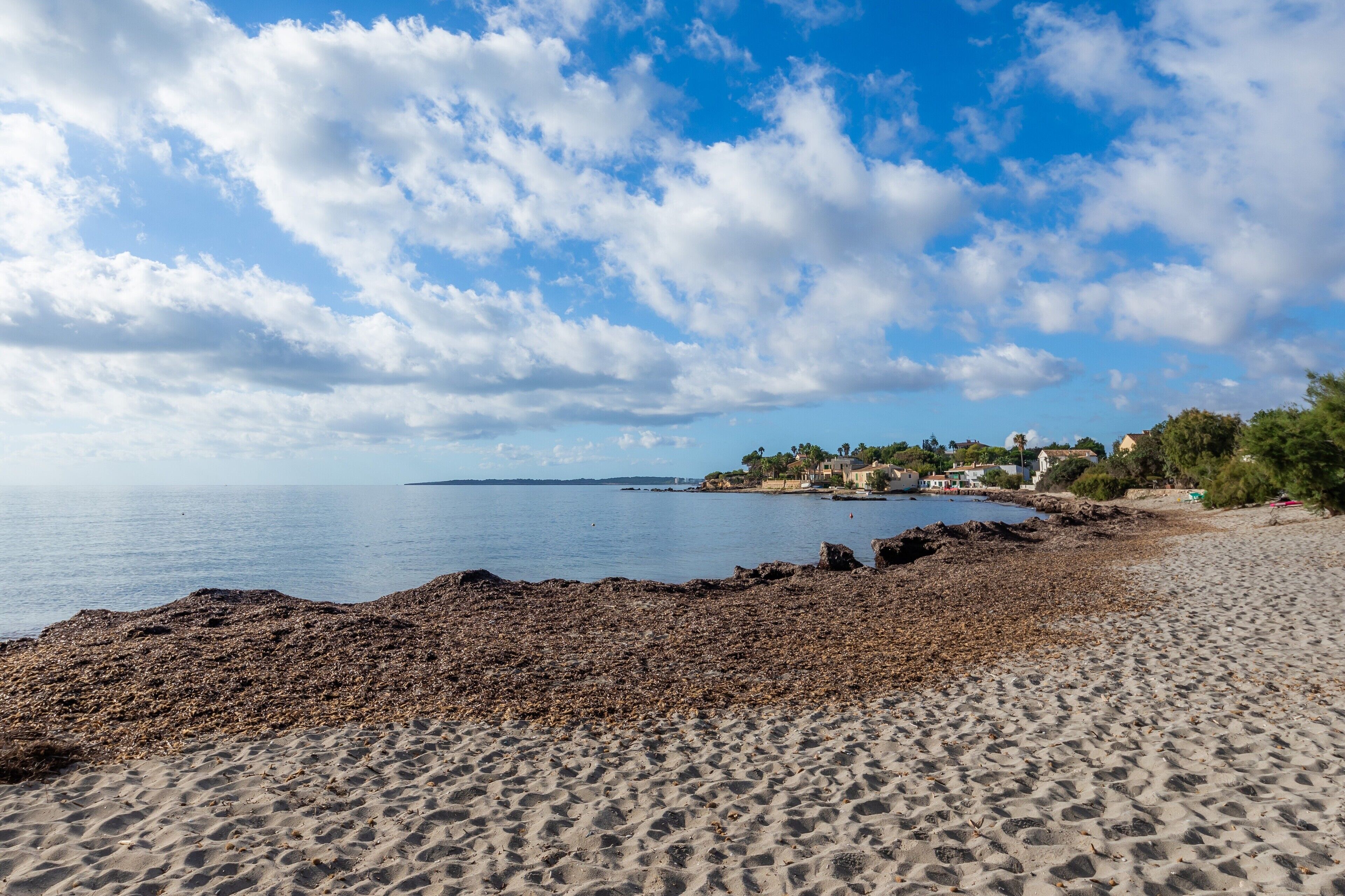 Une plage avec un rivage rocheux, une eau calme et un ciel dégagé.