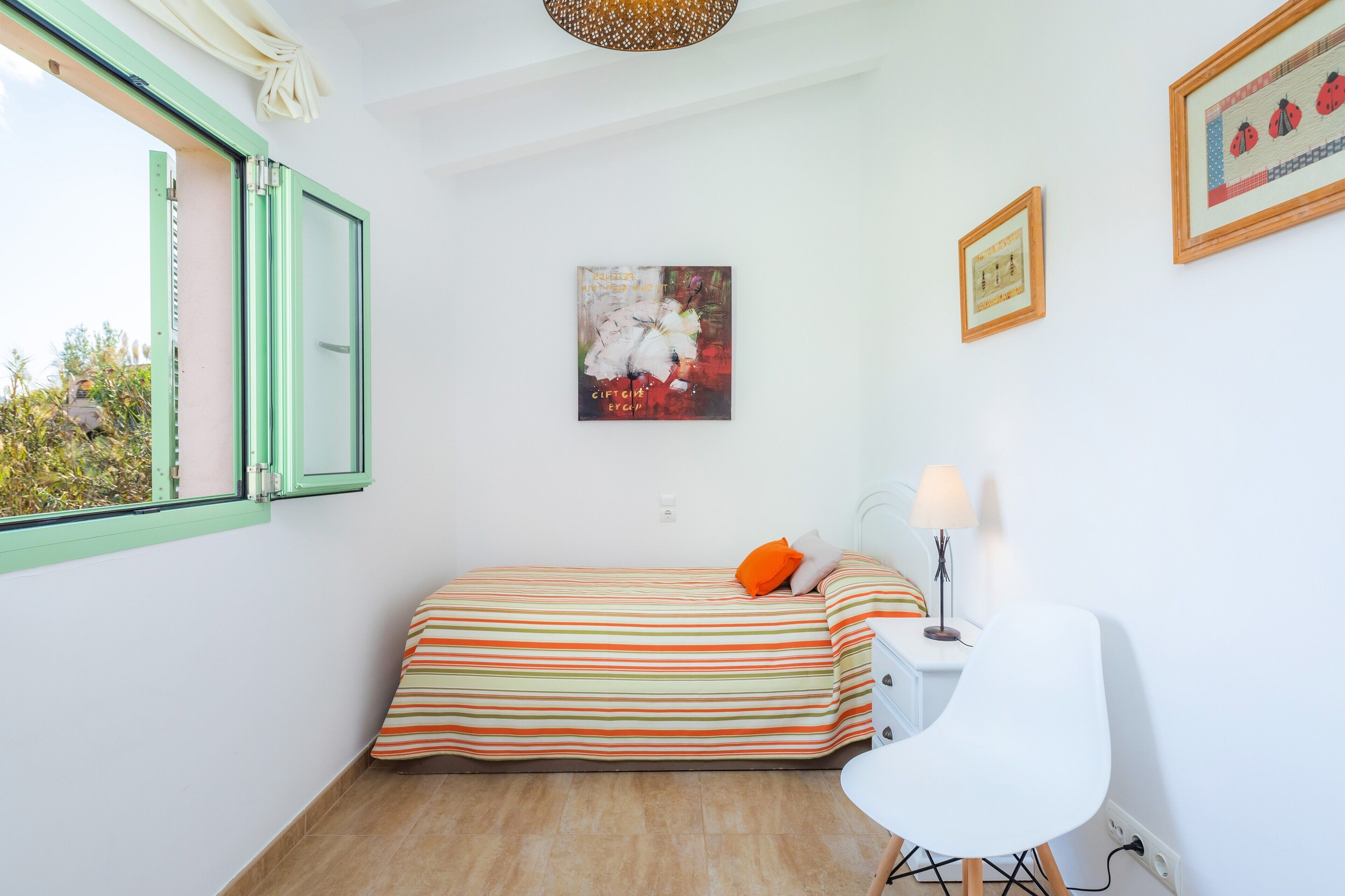 A small room with a bed, a desk, a chair, and a window with curtains.