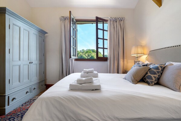 Une chambre à coucher avec un lit, une fenêtre avec des rideaux, une lampe de chevet et une armoire.