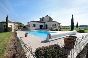 Une maison avec une piscine, un jardin agrémenté de plantes en pot et une clÎture.