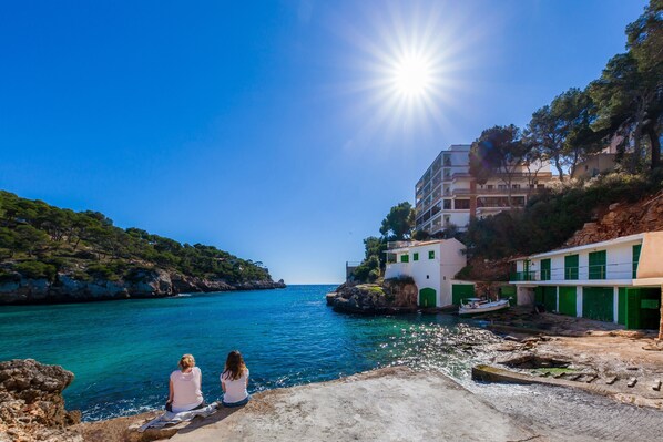 A coastal scene with a clear sky, a body of water, and buildings with green doors.