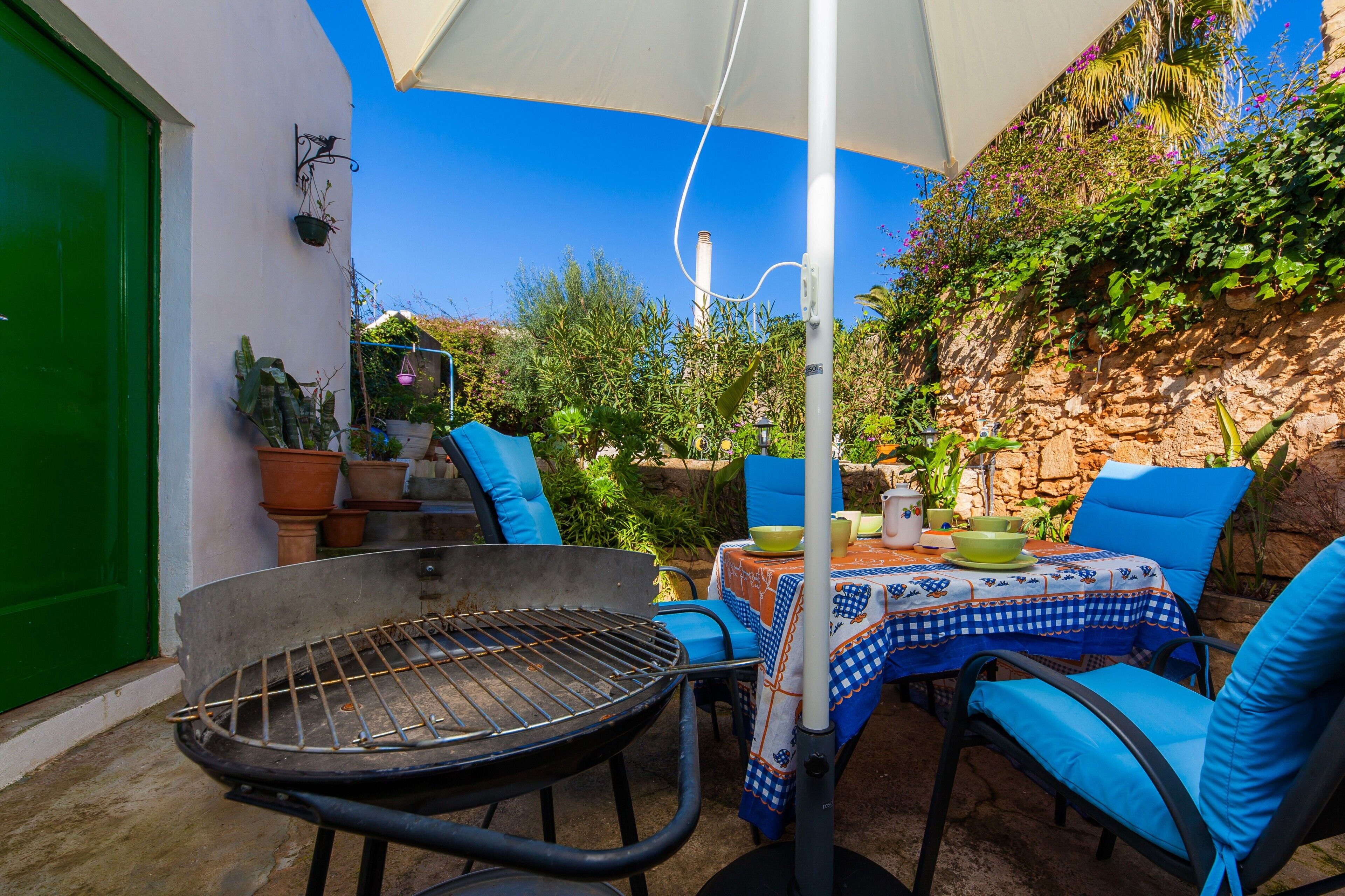 Une terrasse avec un barbecue, une table et des chaises d’extérieur, le tout installé sous une pergola.