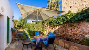 Eine Terrassengruppe mit Tisch und Stühlen, einem großen Sonnenschirm und Blumentöpfen.