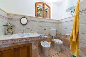 Une salle de bain équipée d’un lavabo, d’un bidet, de toilettes et d’une fenêtre avec un cadre en bois.