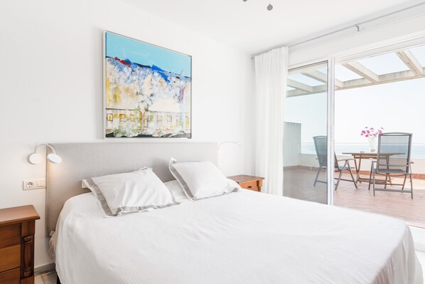 Une chambre d’hôtel avec un lit, une table de chevet, un tableau, une table avec des chaises et une vue sur l’extérieur.