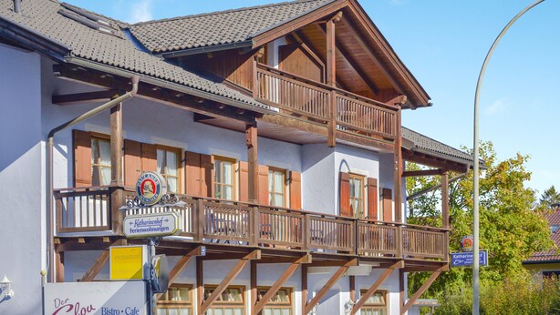 A two-story building with a balcony, wooden railings, and a sign indicating a restaurant.