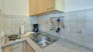 A kitchen with a stainless steel sink, a coffee maker, and a range hood.