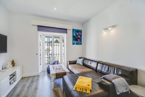 Een moderne woonkamer met een leren bank, een salontafel en een televisie op een witte dressoir.