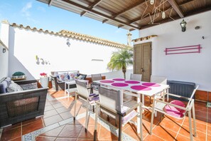 An outdoor patio area with a table and chairs, a wicker sofa, and a potted plant. - Family Chalet with Private Pool and Air Conditioning (Chiclana)
