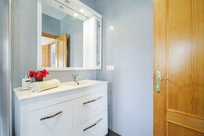A bathroom with a white vanity, a mirror, and a wooden door. - Family Chalet with Private Pool and Air Conditioning (Chiclana)