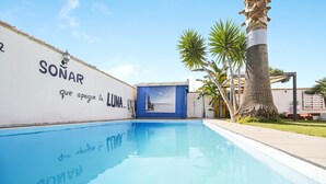 Una piscina con un murale, palme e un edificio con la scritta 'SONAR' e 'que apague la LUNA'.