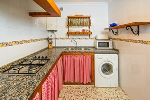 A kitchen with a gas stove, sink, microwave, and washing machine.