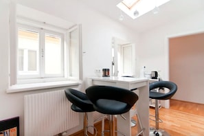 A modern room with a white radiator, a window with blinds, a white desk with a chair, and a mirror.