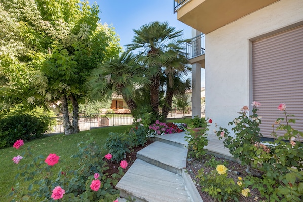 Un quartier résidentiel avec un escalier en béton menant à un garage, le tout entouré d’une végétation luxuriante et de plantes en fleurs.