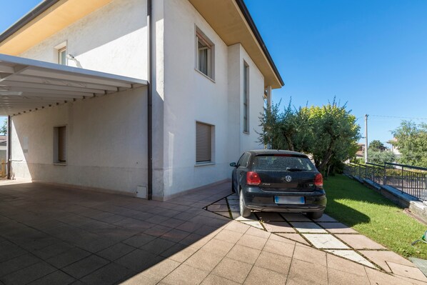 A two-story building with a car parked in the driveway.