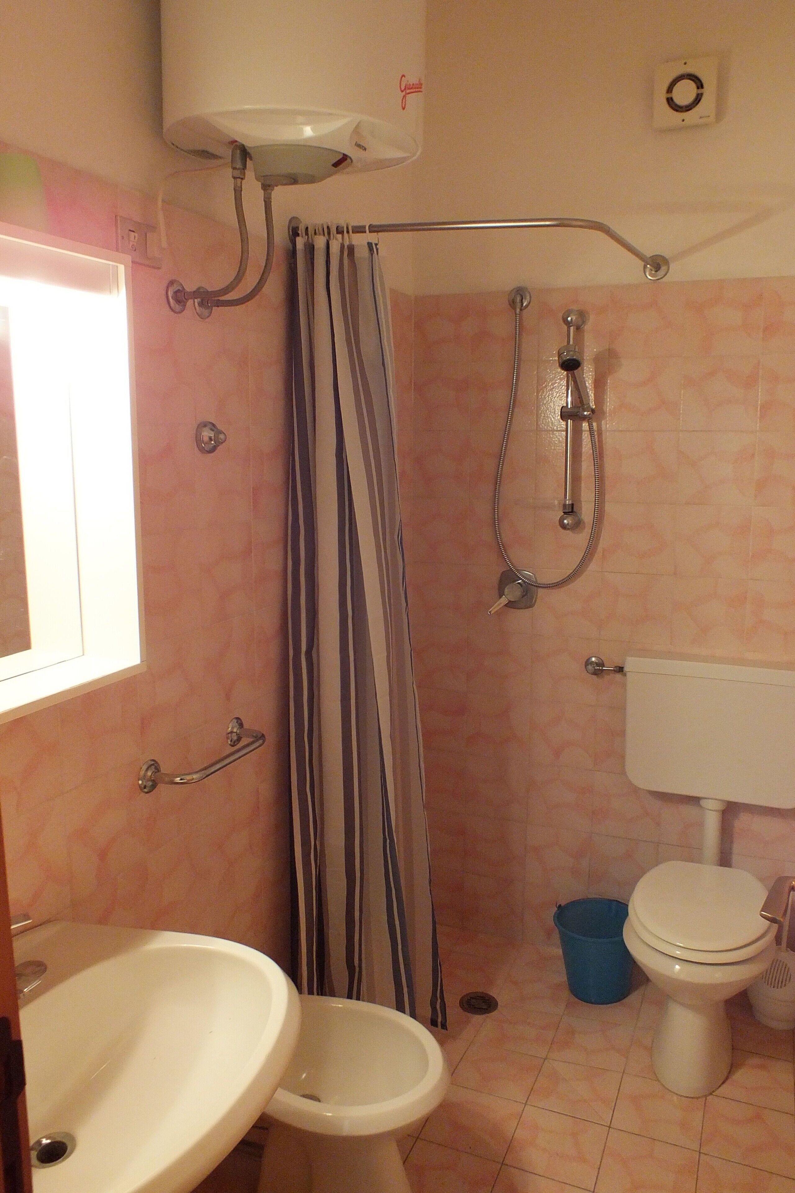 Een badkamer met douche, toilet, wastafel en een gordijn.