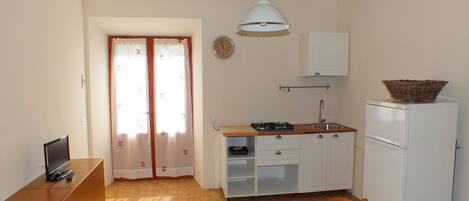 A small kitchen with a refrigerator, stove, sink, and a dining table.