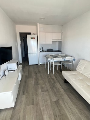 A compact living space with a kitchenette, a dining area with a table and chairs, and a sofa.