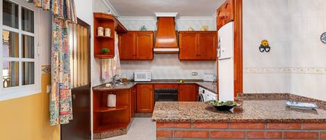 A compact kitchen with wooden cabinets, a built-in brick island, and a microwave.
