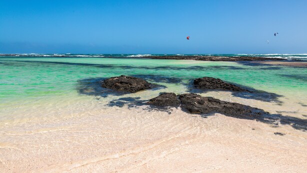 A beach with clear turquoise water, rocky formations, and a distant view of the ocean. - Apartment "Casa Orymar" with Ocean View, Mountain View, Balcony & Terrace (El Cotillo)