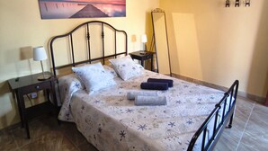 A bedroom with a bed, bedside tables, a nightstand, a mirror, and a painting on the wall. - Apartment "Casa Orymar" with Ocean View, Mountain View, Balcony & Terrace (El Cotillo)
