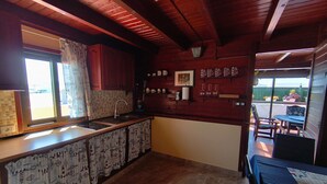 A kitchen with a built-in sink, wooden cabinets, a tiled backsplash, and a dining area with a table and chairs. - Apartment "Casa Orymar" with Ocean View, Mountain View, Balcony & Terrace (El Cotillo)