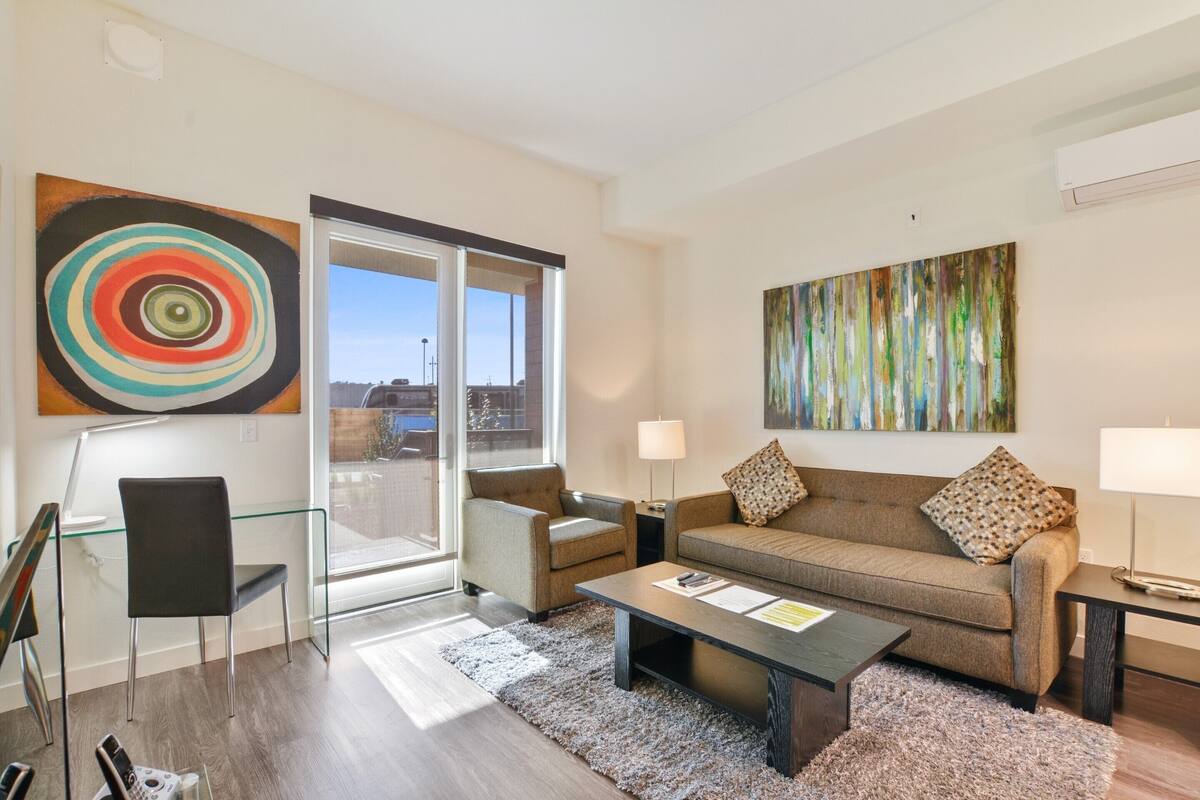 A modern living room with a glass door leading to a balcony, a sofa, a coffee table, and two lamps.