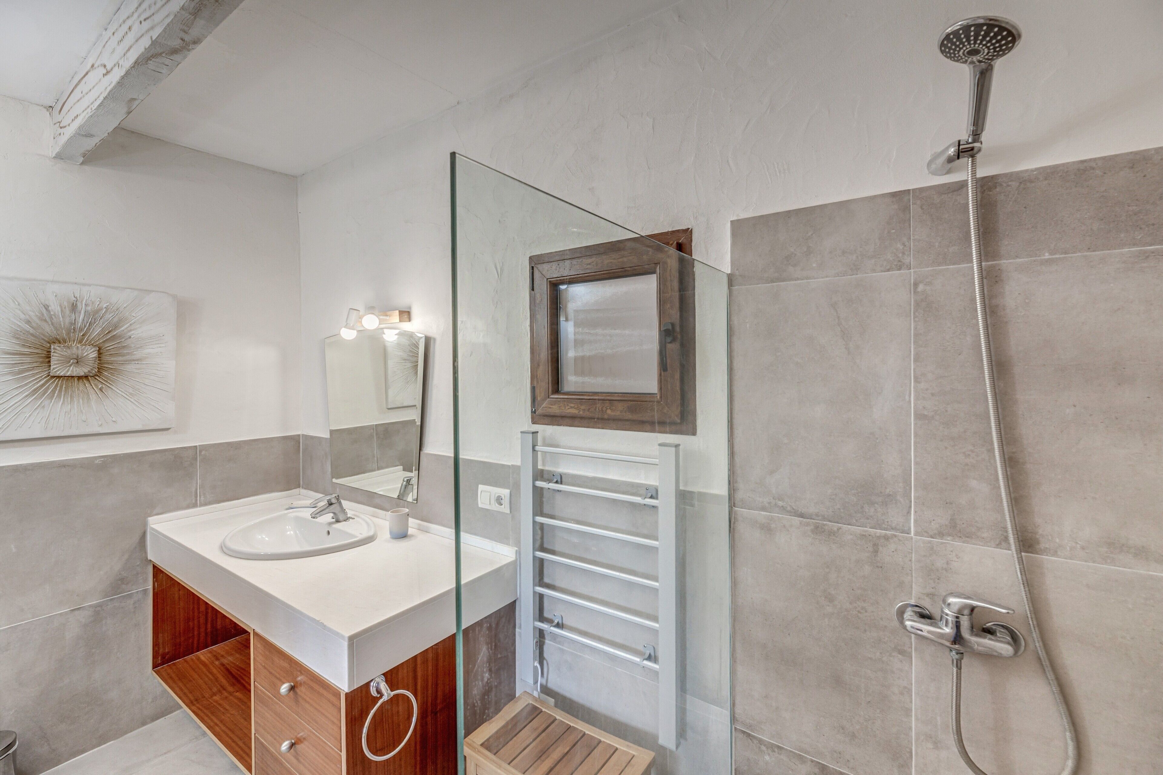 Une salle de bain moderne avec une douche à parois de verre, un meuble-lavabo et un porte-serviettes.
