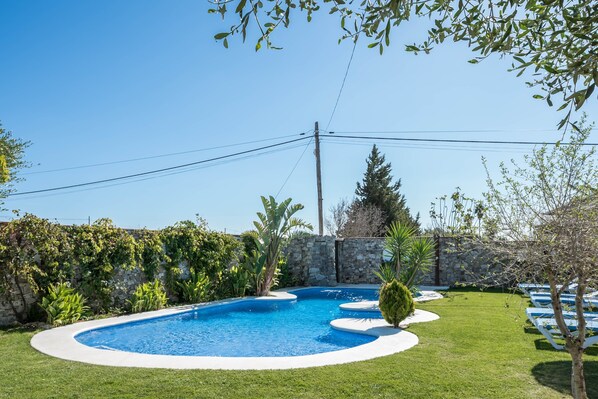 A swimming pool with a stone wall and greenery.